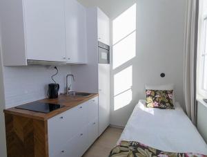 una pequeña cocina blanca con fregadero y cama en Déus Longstay, en Rosersberg