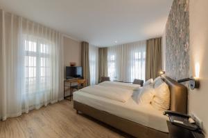 ein Hotelzimmer mit einem großen Bett und zwei Fenstern in der Unterkunft Hof Ehrenfels in Mainz