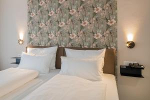 a bed with two white pillows and a floral wallpaper at Hof Ehrenfels in Mainz