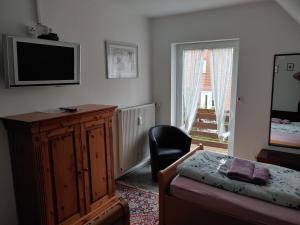 a bedroom with a bed and a television and a chair at Ferienwohnung Weserbergland in Hessisch Oldendorf