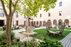 a courtyard with chairs and a tree in front of a building at Ca'di Dio-Small Luxury Hotel in Venice