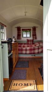 a living room with a bed and a kitchen at Shepherd's Lodge - Shepherd's Hut with Devon Views for up to Two People and One Dog in Wrangaton