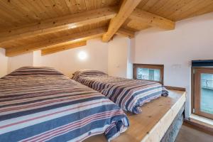 dwa łóżka w pokoju z drewnianym sufitem w obiekcie Agriturismo Al Gallo Nero La Torre w mieście Tenno