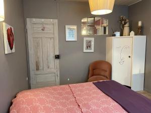 1 dormitorio con cama rosa y nevera blanca en Jardin Secret au Cœur de la Dourd’halie, en Saint-Avold