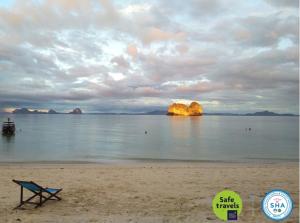 a beach with a bench on the beach with mountains in the water at Koh Ngai Kaimuk Thong Resort in Ko Ngai