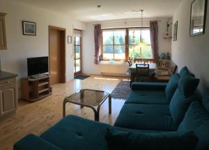 uma sala de estar com um sofá azul e uma mesa em Ferienwohnung-Rottachseeblick em Sulzberg