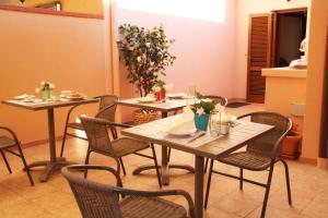 una sala da pranzo con tavoli e sedie con fiori di L'Alloggio-Not just rooms a Olbia