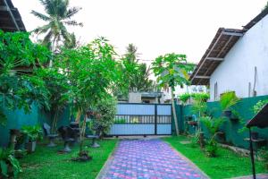 a garden with trees and a fence at Sanda Hiru Guest in Mirissa