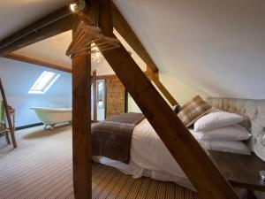 a attic bedroom with a bed and a bath tub at Betsey Trotwood. Historic stylish 2-bed cottage. in Blundeston
