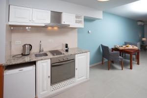 a kitchen with white cabinets and a table at Las Bayas Home Suites in Esquel