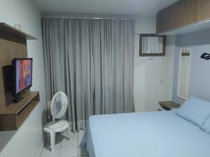 a hotel room with a bed and a tv and a bed and curtains at Apartamento na orla de Maceió in Maceió