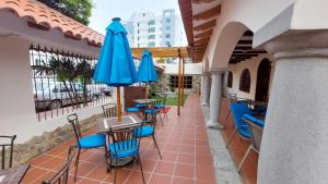 un patio con sillas azules, mesas y sombrillas en Hotel Voyager Manta en Manta