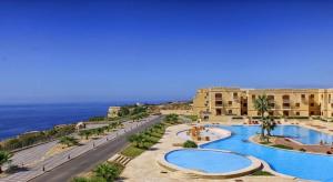 a view of a resort with a swimming pool and the ocean at Luxurious apartment with views of Comino and Malta in Mġarr