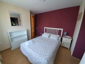 a bedroom with a white bed and a purple wall at El Rincon De Los Abuelos in Tudela de Duero