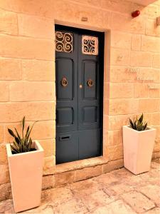 a black door on a brick wall with two potted plants at Città Cospicua suites in Cospicua