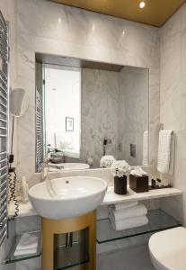 a white bathroom with a sink and a tub at The Excelsior - Small Luxury Hotels of the World in Thessaloniki