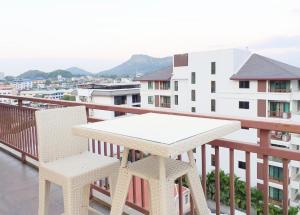 een witte tafel en 2 stoelen op een balkon bij The Sriracha Residence in Si Racha