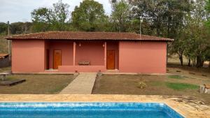 una casa rosa con piscina frente a ella en BANGALÕ DO LAGO en Caconde