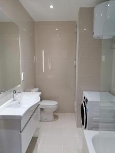 a bathroom with a toilet sink and a washing machine at Luxurious apartment with views of Comino and Malta in Mġarr