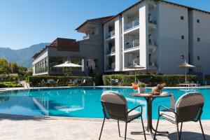 a table and chairs next to a swimming pool at Princess Golden Beach Hotel in Chrysi Ammoudia