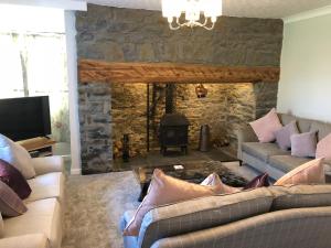 a living room with a couch and a stone fireplace at Pengarreg Fawr in Aberystwyth
