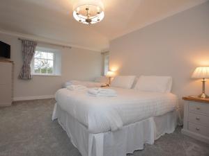 een slaapkamer met een wit bed met 2 lampen en een raam bij Pengarreg Fawr in Aberystwyth