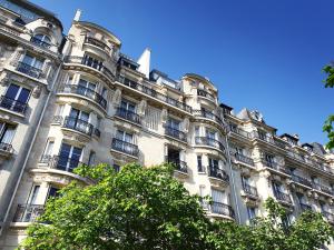 a large white building with balconies and a tree at Outstanding 2 bedrooms with a terrific Eiffel Tower view in Paris