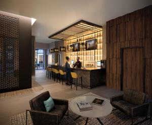 a living room with a bar and a person in a kitchen at voco Times Square South, an IHG Hotel in New York