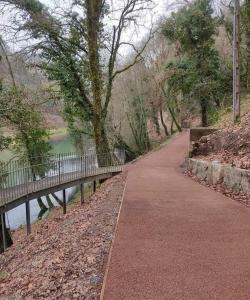a walking path next to a river with a bridge at Casa Morgado in Braga +2 photos