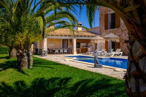 a villa with a swimming pool and palm trees at Mansion Ses Oliveres in S'Horta
