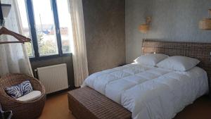 sypialnia z łóżkiem, krzesłem i oknami w obiekcie chez David w mieście Bressuire