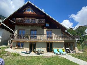 ein Haus mit einem Balkon, einem Tisch und Stühlen in der Unterkunft La Tanière in Vaujany