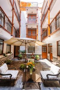 an outdoor patio with chairs and an umbrella at El Portal De San Lázaro in Arequipa