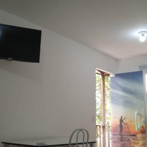 une télévision sur un mur avec une peinture d'homme dans l'établissement A Casa da Ilha de Itacuruçá - Aps, à Flecheiras