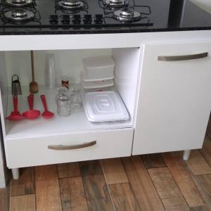 um armário de cozinha branco com um fogão e alguns utensílios em A Casa da Ilha de Itacuruçá - Aps em Flecheiras