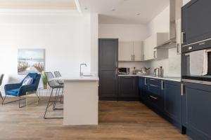 a kitchen with blue cabinets and a white counter top at Skye Sands - Swilken Garden Residence - St Andrews in St. Andrews