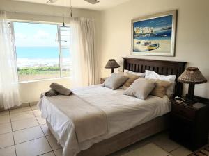 a bedroom with a bed with a view of the ocean at 3 Marina Palms, Woodgrange-on-sea in Hibberdene