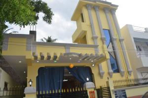 una casa amarilla con una cortina azul delante de ella en Vasantham Villas en Pondicherry