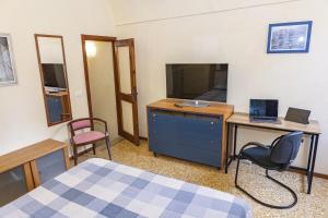Schlafzimmer mit einem Schreibtisch, einem TV und einem Bett in der Unterkunft Centralissimo Trilocale su due piani - Flavio House in Sanremo