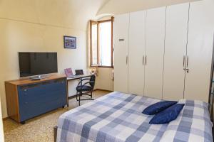 Schlafzimmer mit einem Bett, einem Schreibtisch und einem TV in der Unterkunft Centralissimo Trilocale su due piani - Flavio House in Sanremo