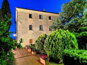 ein großes Backsteingebäude mit Pflanzen davor in der Unterkunft Hotel Residence Villa Rioddi in Volterra