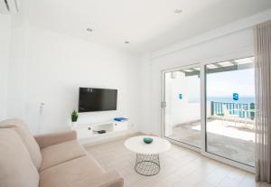 sala de estar con sofá, TV y balcón en Blancazul Los Clicos, en Playa Blanca