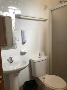 uma casa de banho branca com um WC e um lavatório em Hostal Malania em Manta