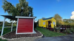a yellow and red garage next to a tiny house at Ferienhaus Tiny Löwenzahn in Visselhövede