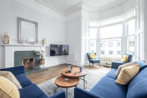 a living room with a blue couch and a table at Skye Sands - Alexandra Penthouse - St Andrews in St. Andrews