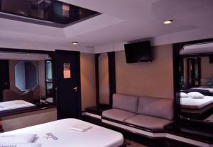 um quarto com um sofá, uma cama e uma televisão em Hotel Xanadu - Adults Only no Rio de Janeiro