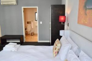 um quarto com uma cama branca e um candeeiro vermelho em 1 Bedroom Apartment with Roof Top Views em Cidade do Cabo
