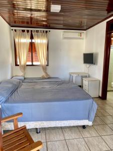 a bedroom with a blue bed and a television at CASA BEIRA MAR NA BARRA DE SÃO MIGUEL in Barra de São Miguel +3 photos