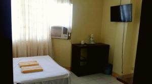 a room with a bed and a television and a window at JR Pension House in Baybay