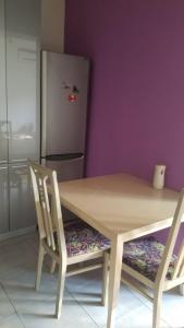 uma mesa de madeira com 2 cadeiras e um frigorífico em Empire Apartments em Skopje